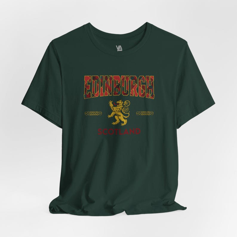 Puede incluir: Camiseta verde oscuro con la palabra "EDINBURGH" en un dise&ntilde;o de cuadros, un emblema de le&oacute;n dorado y la palabra "SCOTLAND" en rojo. La camiseta tiene mangas cortas y cuello redondo.