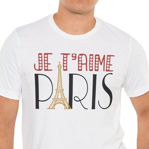 A man wearing a white tshirt that says "Je T'aime Paris". The A in "Paris" is replaced with a graphic of the Eiffel Tower.