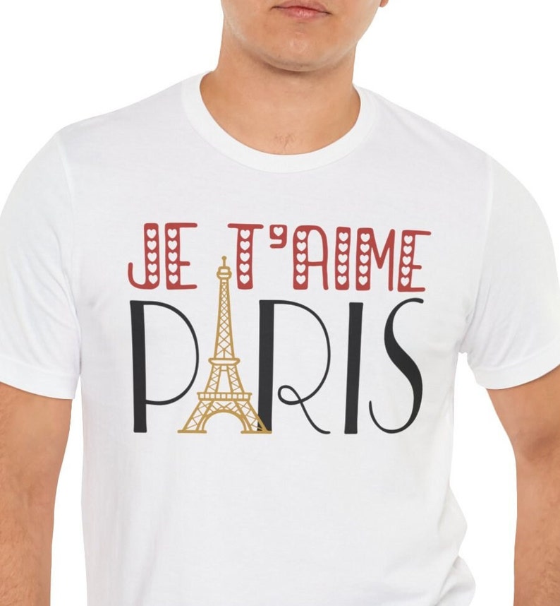 A man wearing a white tshirt that says "Je T'aime Paris". The A in "Paris" is replaced with a graphic of the Eiffel Tower.