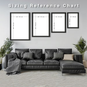 May include: A white wall with four black framed pictures of different sizes. The pictures are arranged in a row from left to right. The pictures are labeled with their dimensions in inches and centimeters. The pictures are hanging above a black leather sectional sofa with gray throw pillows and a gray throw blanket.