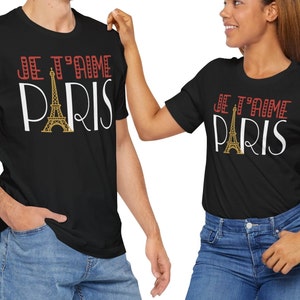 A man andwoman wearing matching tshirts that says "Je T'aime Paris". The A in "Paris" is replaced with a graphic of the Eiffel Tower.