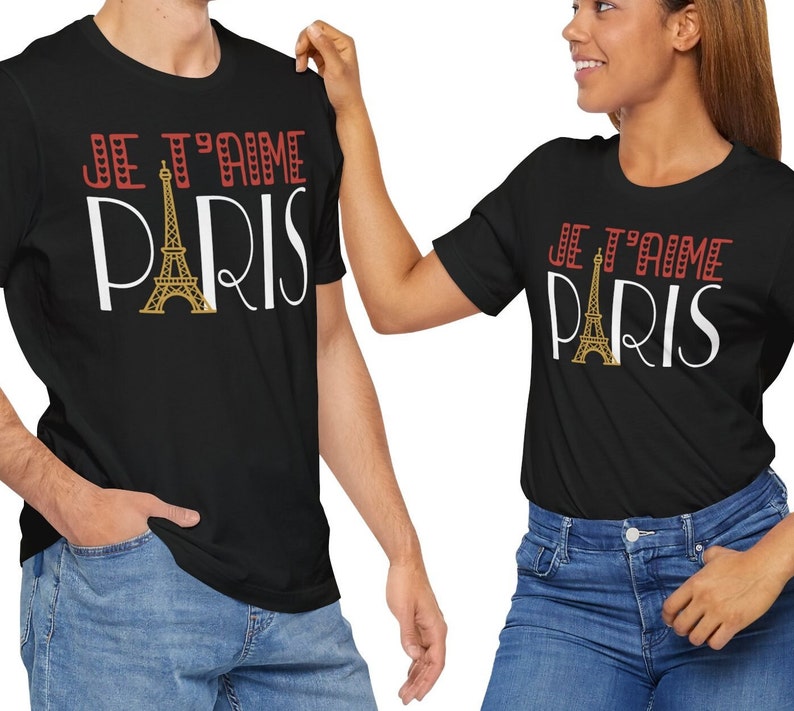 A man andwoman wearing matching tshirts that says "Je T'aime Paris". The A in "Paris" is replaced with a graphic of the Eiffel Tower.