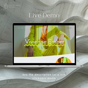 May include: A laptop computer displaying a website with the text "Vivienne Ember" in a yellow and white wavy design. The website is on a white background with a gray and white textured background behind the laptop.