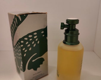 May include: A green and silver box with a green leaf design and a clear glass bottle of perfume with a green cap.