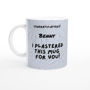 Puede incluir: Taza de cerámica blanca con una superficie texturizada gris. La taza tiene texto negro que dice "¡Felicidades! Benny ¡He enyesado esta taza para ti!"