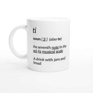 May include: White ceramic mug with a black definition of the word "ti" printed on it. The definition reads: "noun [S] (also te) the seventh note in the sol-fa musical scale A drink with jam and bread"