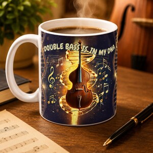 May include: A white ceramic mug featuring a dark blue background with a glowing golden DNA double helix structure, a brown double bass, musical notes, and the text "DOUBLE BASS IS IN MY DNA" printed in a light yellow font on the front surface.