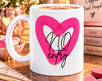 Può includere: Una tazza in ceramica bianca con un grande cuore rosa acceso dipinto a mano sulla parte anteriore. Al centro del cuore si trova la scritta in corsivo nero "NO entry". La tazza presenta una finitura liscia e lucida con un manico curvo.