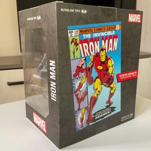 May include: A rectangular box featuring a comic book cover of Iron Man. The box has a clear plastic window. The Iron Man comic cover is red, yellow, and blue. The box is labeled "McFarlane Toys" and "Marvel".