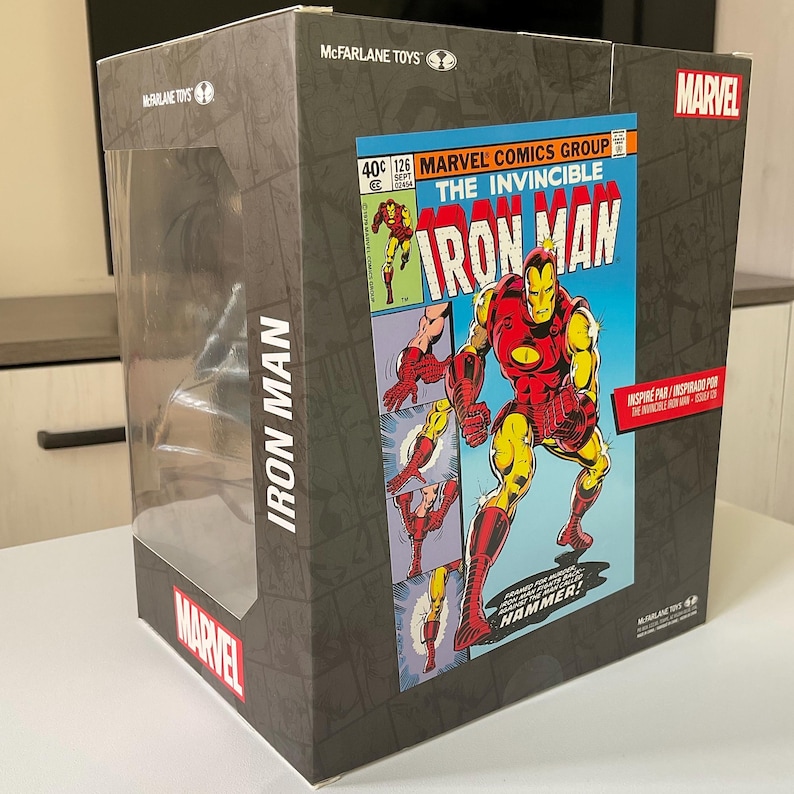 May include: A rectangular box featuring a comic book cover of Iron Man. The box has a clear plastic window. The Iron Man comic cover is red, yellow, and blue. The box is labeled "McFarlane Toys" and "Marvel".