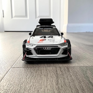 May include: White and red Audi S line quattro race car with a black roof rack and a black luggage carrier. The car has the number 44 on the side and the Audi logo on the front.