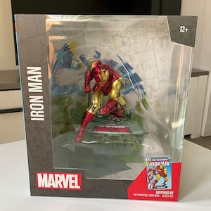 Könnte beinhalten: Eine verpackte Iron Man-Figur in dynamischer Pose mit roter und goldener Rüstung. Die Verpackung enthält das Marvel-Logo und den Text "IRON MAN" und "INSPIRED BY THE INVINCIBLE IRON MAN - ISSUE# 125". Die Figur ist für Kinder ab 12 Jahren geeignet.