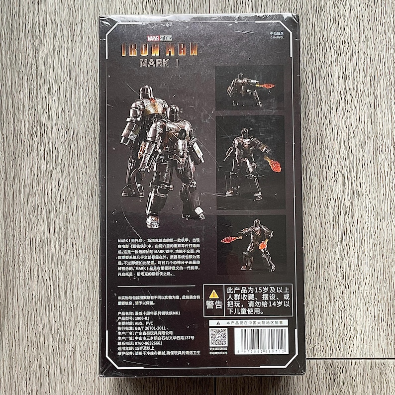 Może przedstawiać: Opakowanie figurki Iron Man Mark 1. Pudełko zawiera zdjęcia figurki w r&oacute;żnych pozach, z logo Marvel Studios. Figurka to szczeg&oacute;łowy, metaliczny przedmiot kolekcjonerski.