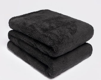 May include: A soft, plush charcoal gray throw blanket folded in half. The blanket is made of a fuzzy, textured fabric.