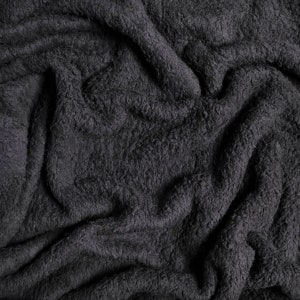 May include: Close-up of a soft, dark gray, fluffy fabric with a wrinkled texture.