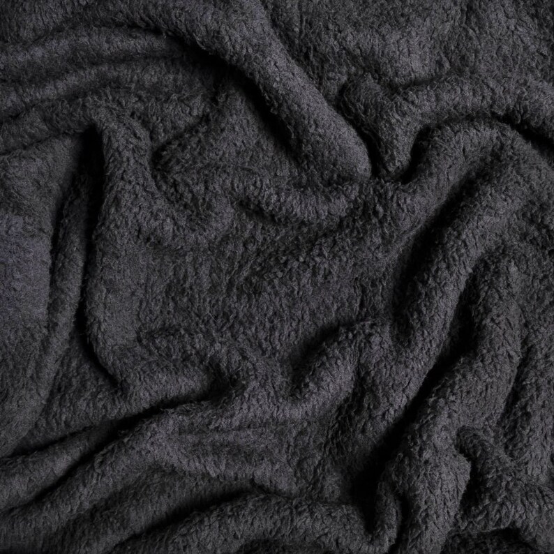 May include: Close-up of a soft, dark gray, fluffy fabric with a wrinkled texture.