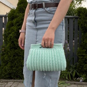 Handmade crochet clutch bag featuring a modern ribbed texture and minimalist design. Stylish crocheted purse made from chunky yarn, perfect for everyday wear, special occasions, and evening outings. The elegant rectangular shape adds a contemporary touch to any outfit. Detailed crochet stitches create a unique texture that makes this bag both fashionable and eye-catching.
