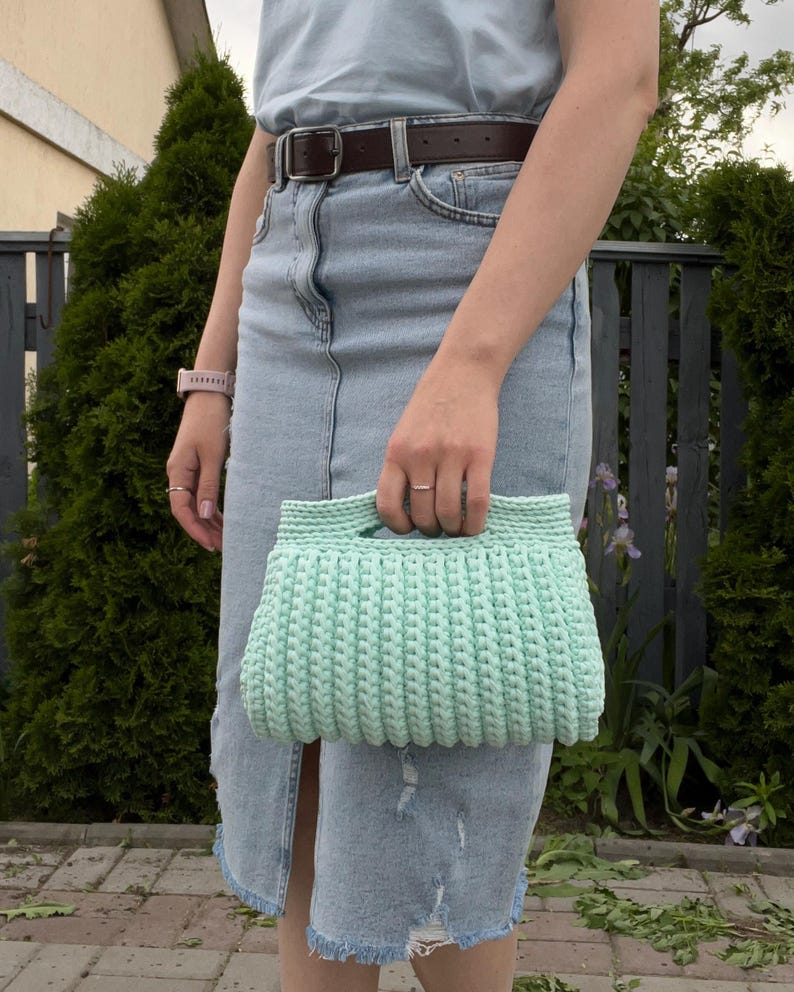 Handmade crochet clutch bag featuring a modern ribbed texture and minimalist design. Stylish crocheted purse made from chunky yarn, perfect for everyday wear, special occasions, and evening outings. The elegant rectangular shape adds a contemporary touch to any outfit. Detailed crochet stitches create a unique texture that makes this bag both fashionable and eye-catching.