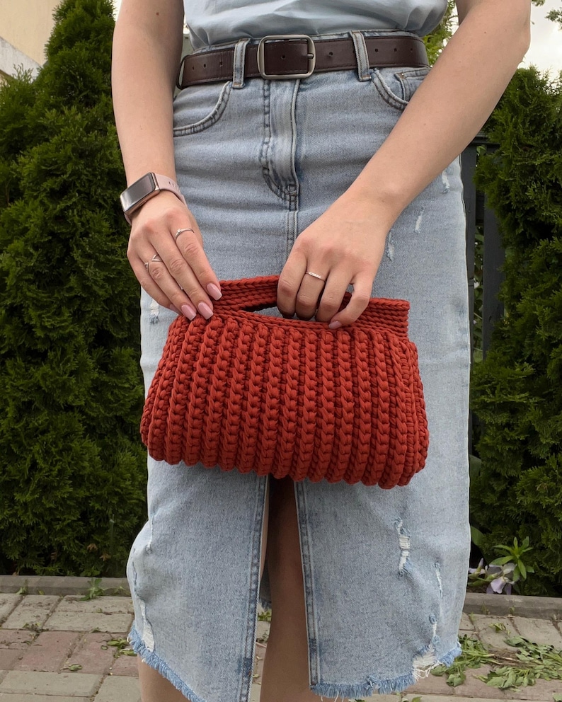 Handmade crochet clutch bag featuring a modern ribbed texture and minimalist design. Stylish crocheted purse made from chunky yarn, perfect for everyday wear, special occasions, and evening outings. The elegant rectangular shape adds a contemporary touch to any outfit. Detailed crochet stitches create a unique texture that makes this bag both fashionable and eye-catching.