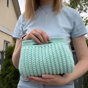 Handmade crochet clutch bag featuring a modern ribbed texture and minimalist design. Stylish crocheted purse made from chunky yarn, perfect for everyday wear, special occasions, and evening outings. The elegant rectangular shape adds a contemporary touch to any outfit. Detailed crochet stitches create a unique texture that makes this bag both fashionable and eye-catching.