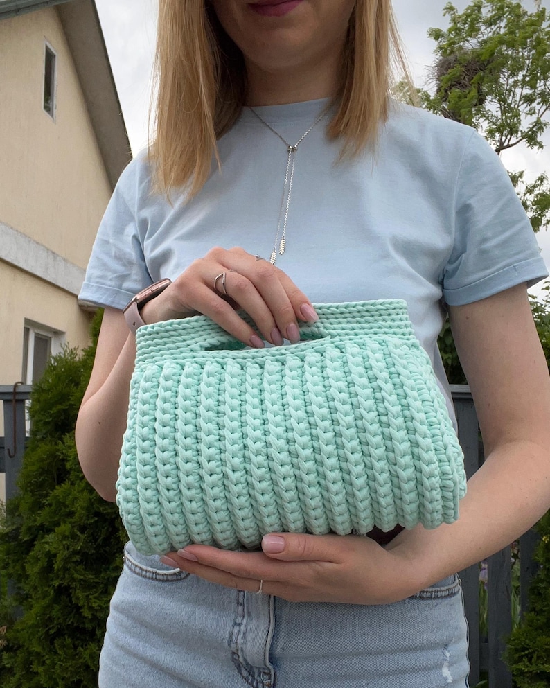 Handmade crochet clutch bag featuring a modern ribbed texture and minimalist design. Stylish crocheted purse made from chunky yarn, perfect for everyday wear, special occasions, and evening outings. The elegant rectangular shape adds a contemporary touch to any outfit. Detailed crochet stitches create a unique texture that makes this bag both fashionable and eye-catching.