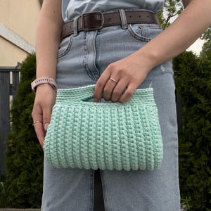 Handmade crochet clutch bag featuring a modern ribbed texture and minimalist design. Stylish crocheted purse made from chunky yarn, perfect for everyday wear, special occasions, and evening outings. The elegant rectangular shape adds a contemporary touch to any outfit. Detailed crochet stitches create a unique texture that makes this bag both fashionable and eye-catching.