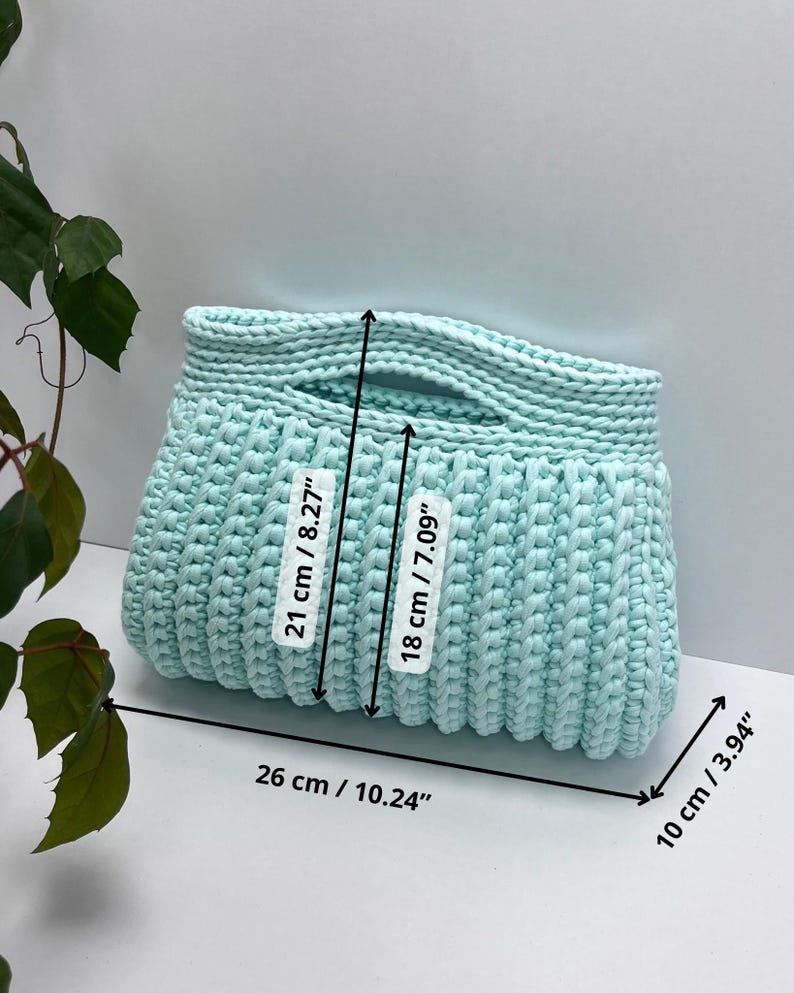 Handmade crochet clutch bag featuring a modern ribbed texture and minimalist design. Stylish crocheted purse made from chunky yarn, perfect for everyday wear, special occasions, and evening outings. The elegant rectangular shape adds a contemporary touch to any outfit. Detailed crochet stitches create a unique texture that makes this bag both fashionable and eye-catching.