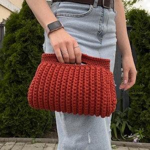 Handmade crochet clutch bag featuring a modern ribbed texture and minimalist design. Stylish crocheted purse made from chunky yarn, perfect for everyday wear, special occasions, and evening outings. The elegant rectangular shape adds a contemporary touch to any outfit. Detailed crochet stitches create a unique texture that makes this bag both fashionable and eye-catching.