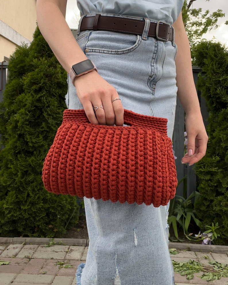 Handmade crochet clutch bag featuring a modern ribbed texture and minimalist design. Stylish crocheted purse made from chunky yarn, perfect for everyday wear, special occasions, and evening outings. The elegant rectangular shape adds a contemporary touch to any outfit. Detailed crochet stitches create a unique texture that makes this bag both fashionable and eye-catching.