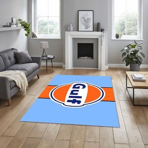 Può includere: Un tappeto blu e arancione con il logo Gulf al centro. Il logo è un cerchio con la parola "Gulf" in lettere bianche.