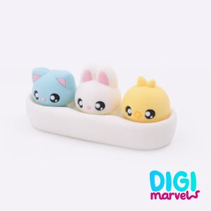 May include: A white, oblong container holds three cartoon animal figures. A light blue cat, a white bunny with pink ears, and a yellow chick with a bow. The figures have large black eyes and are set against a white background. The text "DIGI marvels" is in the bottom right.