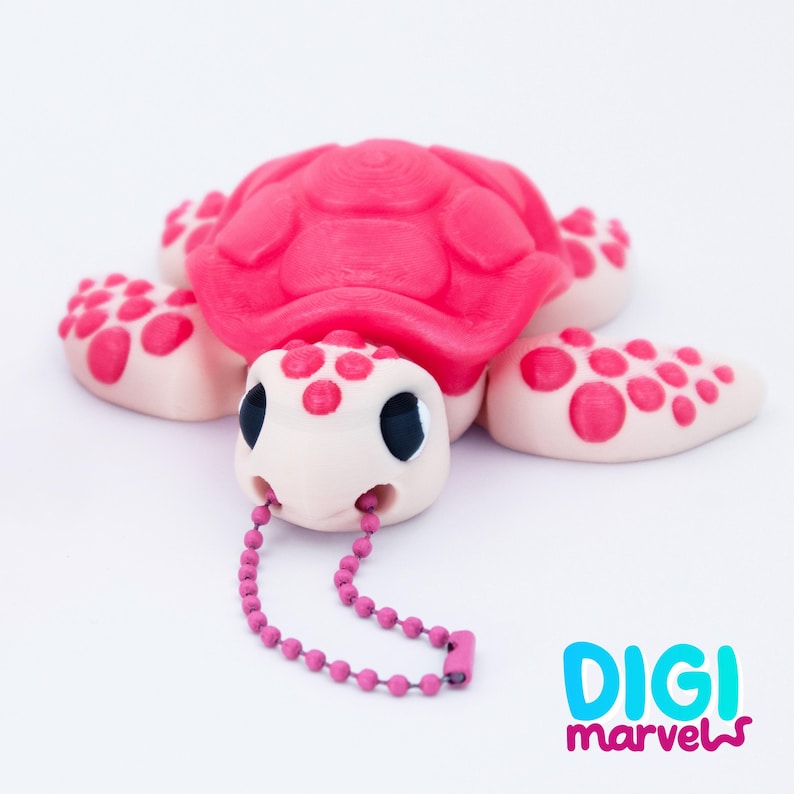 May include: A pink turtle figurine with a textured shell and dotted flippers. The turtle's head is off-white with black eyes and a pink beaded chain. The Digi Marvels logo is in the bottom right corner.