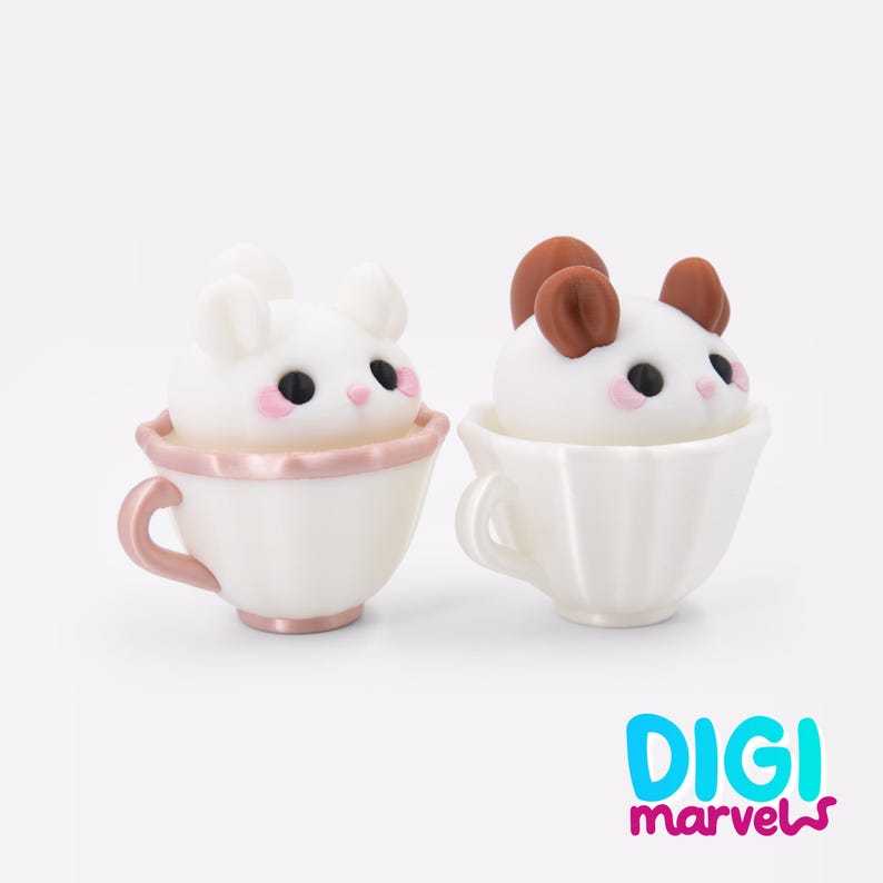 Puede incluir: Dos peque&ntilde;as figuras de criaturas blancas con ojos negros y mejillas rosadas, cada una sentada dentro de una taza de t&eacute; estriada. La taza izquierda es blanca con asa y borde rosa met&aacute;lico, la derecha es blanca. Se ve el texto DIGI marvels.
