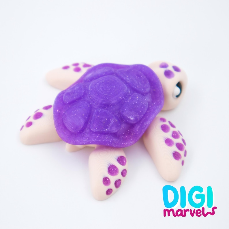 May include: A handcrafted turtle figurine with a vibrant purple shell and light tan body. The shell has a textured surface with glitter, and the flippers are adorned with purple polka dots. The figurine is set against a white background.
