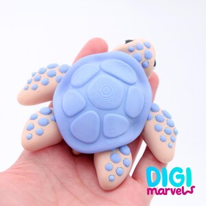 May include: A light blue turtle figurine with a textured shell and light tan flippers. The flippers have blue polka dots. The figurine is held in a hand. The logo "DIGI marvels" is in the bottom right corner.