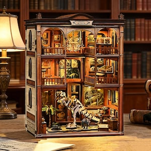 Op de afbeelding: Gedetailleerd houten model van een fossielenmuseum, met meerdere verdiepingen en miniatuurexposities, waaronder dinosaurus skeletten en fossielen. Het gebouw heeft een donkerbruine buitenkant met boogvensters en een bord met "Fossil Museum".