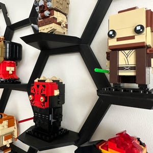 May include: A black hexagonal shelf unit with various Star Wars Lego minifigures displayed on it. The minifigures include Darth Maul, a Tusken Raider, a Jedi, and a Sith.