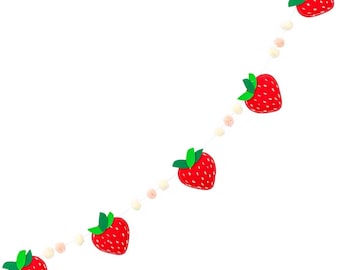 May include: A decorative garland featuring five red strawberry cutouts with green leaves and white seed details, interspersed with small, round, cream and light pink pom-poms strung along a thin, light-colored cord against a white background.