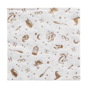 Puede incluir: Servilleta de papel cuadrada blanca con un patr&oacute;n repetido de ilustraciones doradas. El dise&ntilde;o incluye estrellas, rayos, gafas, b&uacute;hos, escobas y la letra "H".