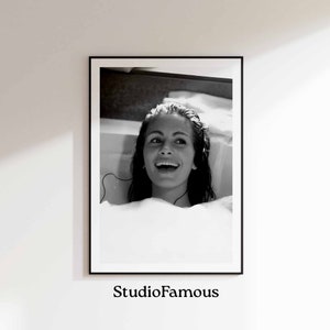 Può includere: Fotografia in bianco e nero di una donna con i capelli lunghi che sorride mentre è seduta in una vasca da bagno. La donna indossa delle cuffie e guarda in alto.