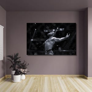 Könnte beinhalten: Schwarz-Weiß-Fotografie eines Mannes, der mit erhobenen Armen jubelt. Das Bild konzentriert sich auf den Oberkörper des Mannes, mit einer Menschenmenge und hellem Licht im Hintergrund. Der Mann trägt Shorts mit dem Wort "CONOR".