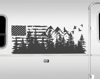 May include: A white camper van with a black silhouette decal of a mountain range, forest, and American flag on the side. The decal features birds flying above the mountains.