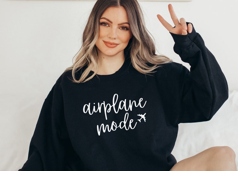 May include: Black sweatshirt with the words "airplane mode" in white script, accompanied by a small airplane graphic. The sweatshirt is a casual style, suitable for travel or everyday wear.