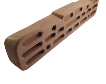Puede incluir: Una presa de escalada de madera con múltiples agarres para los dedos de diferentes tamaños y formas. La presa está hecha de madera natural y tiene un color marrón claro.