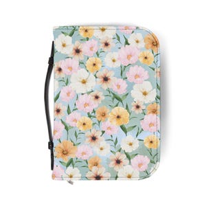 May include: A floral-patterned case with a black handle. The case features a light blue background with a repeating pattern of white, pink, and yellow flowers and green leaves. The case is closed with a zipper.