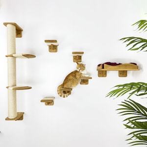 May include: A cat tree with multiple platforms and a scratching post. The cat tree is made of wood and has a natural finish. The cat tree is mounted on a white wall. A cat is sitting on one of the platforms.