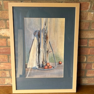 May include: A framed watercolor painting of a weathered wooden post with a rope wrapped around it. There are five red apples at the base of the post.