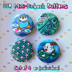 May include: Set of four 1-inch pinback buttons featuring characters and designs from the popular video game Dance Dance Revolution (DDR). The buttons feature a blue penguin, a green rocket, a green arrow pattern, and a white ghost.