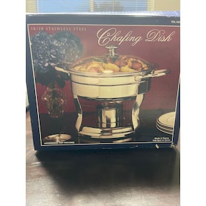 May include: A stainless steel chafing dish with a clear glass lid, displayed in its original box. The box features text that reads "18/10 Stainless Steel" and "Chafing Dish". The box also states "Accessories Not Included".