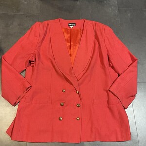 May include: A coral double-breasted blazer with gold buttons. The blazer features a notched lapel and two front pockets. The interior lining is bright orange. The blazer is a vintage style.